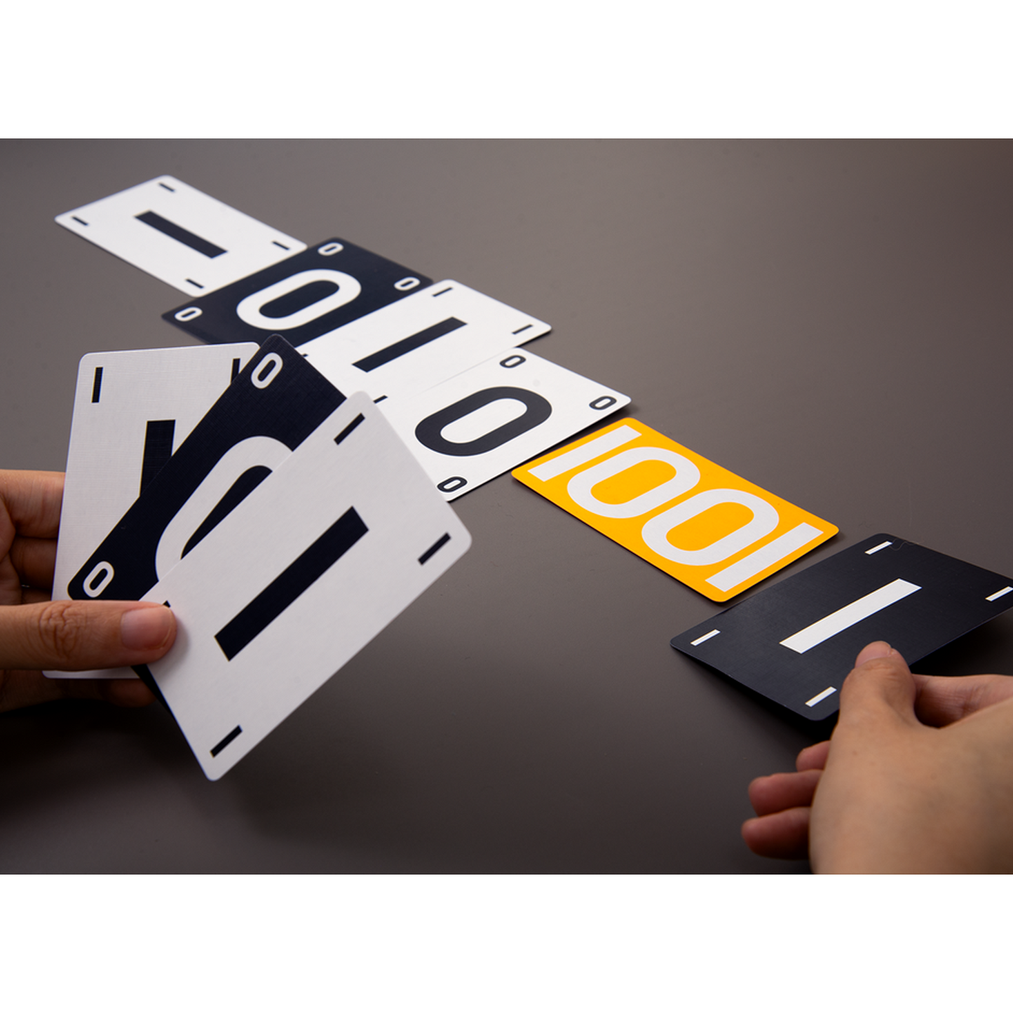 Compress Board Game Being Played on a Dark Grey Table and Showing a Line of White, Black and Orange Cards with 1's and 0's on them | Happy Piranha