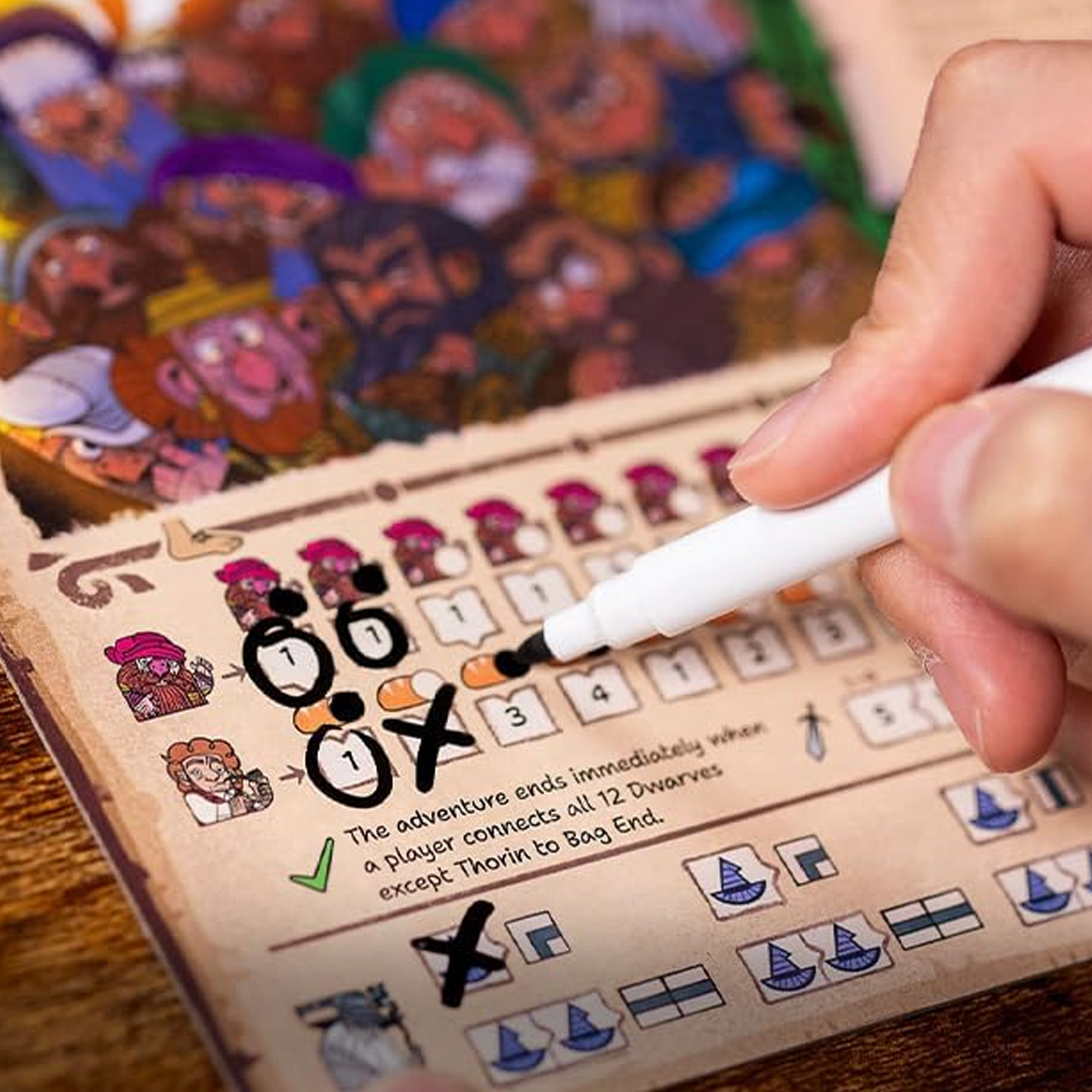 The Hobbit There & Back Again Board Game - A Close Up of a Persons Hand Marking a Box with a Drywipe Marker on a Colourfully Illustrated Pad | Happy Piranha