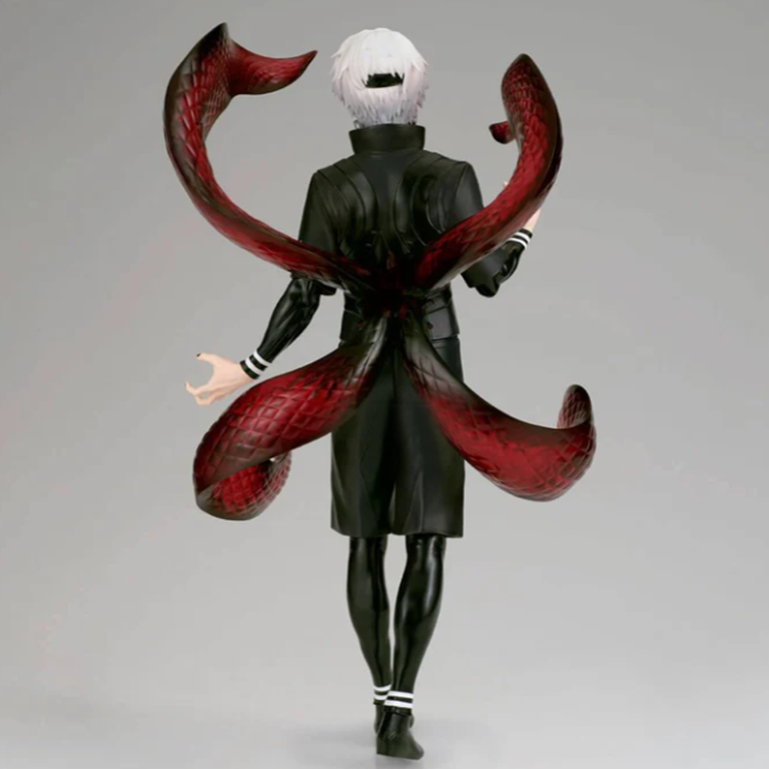 A collectible action figure of the character Ken Kaneki from Tokyo Ghoul, shown from the back with his signature red tentacles spread across his back, wearing a black coat and white hair, set against a plain gray studio background | Tokyo Ghoul Ken Kaneki Grandista Figure | Happy Piranha