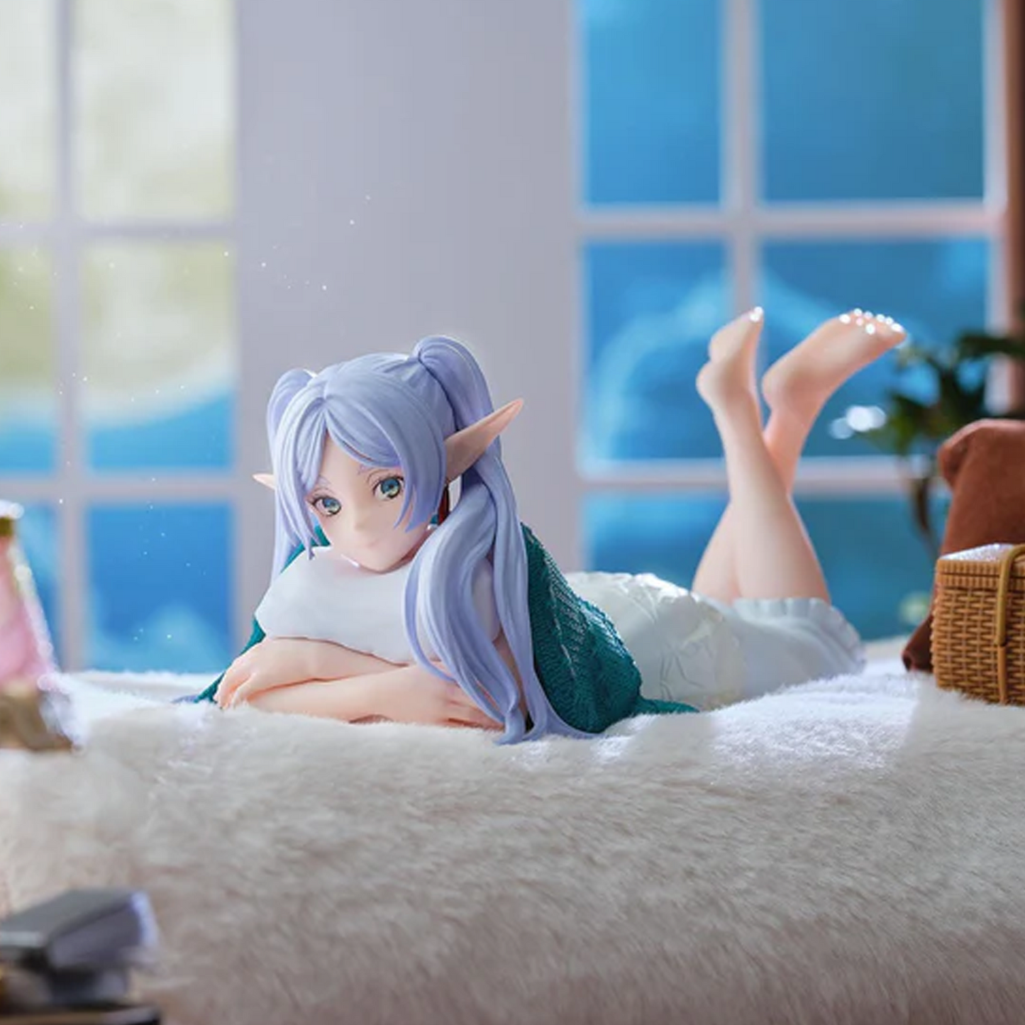 Anime-style elf girl figurine with long lavender-blue hair, reclining on a white fluffy bed or rug in a softly lit room. She wears a white top and teal-green skirt, with one leg bent upward  Roomwear: Frieren Beyond Journey's End Yumemirize Figure  Happy Piranha