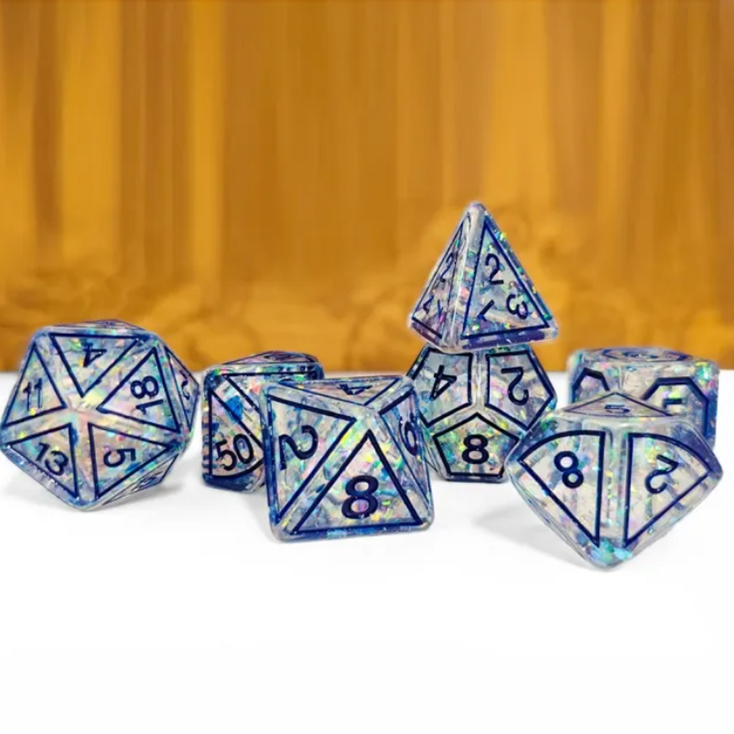 Blue Magic Stone Design Glitter Polyhedral Dice Set Stacked in a Pile on a White and Wood Coloured Background | Happy Piranha