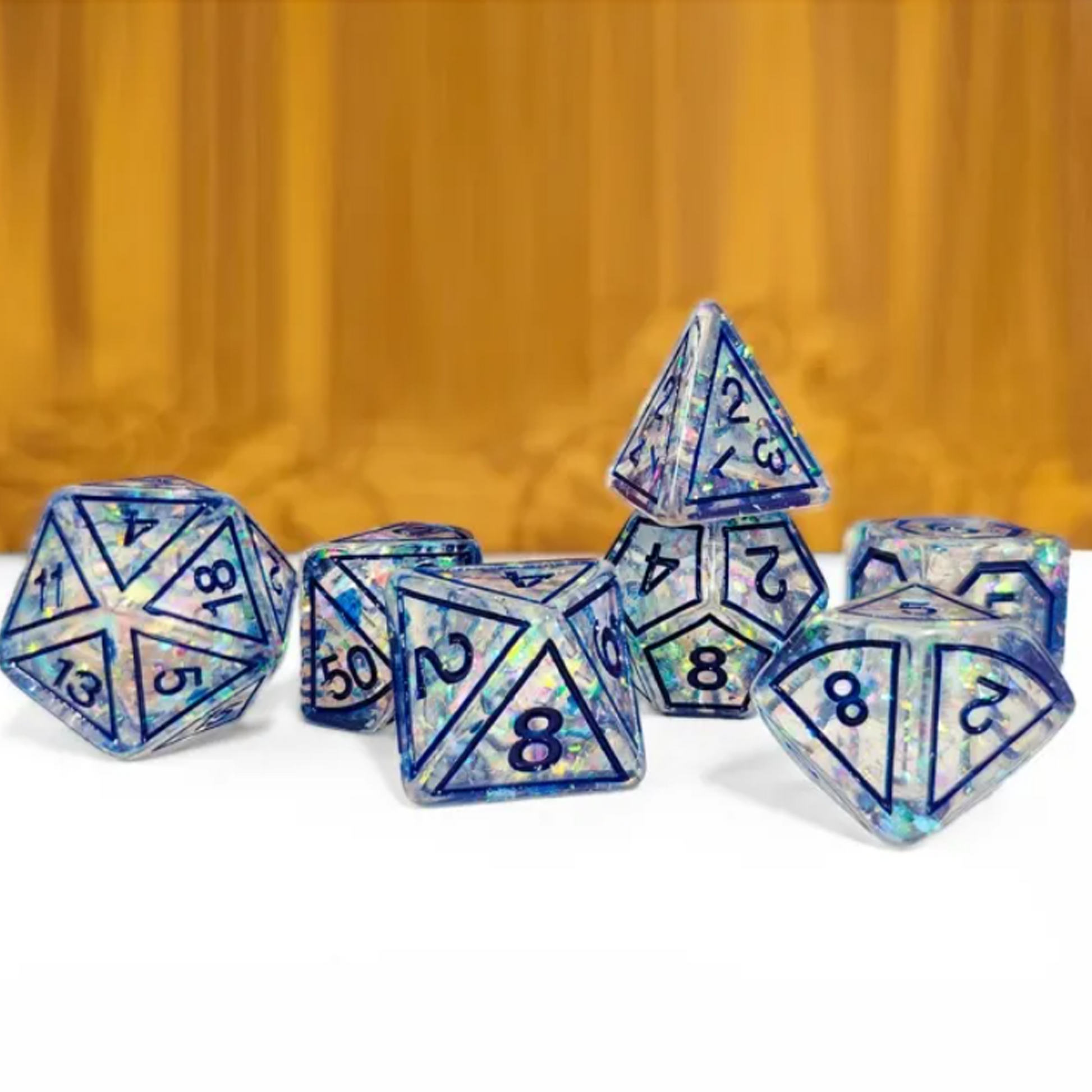 Blue Magic Stone Design Glitter Polyhedral Dice Set Stacked in a Pile on a White and Wood Coloured Background | Happy Piranha