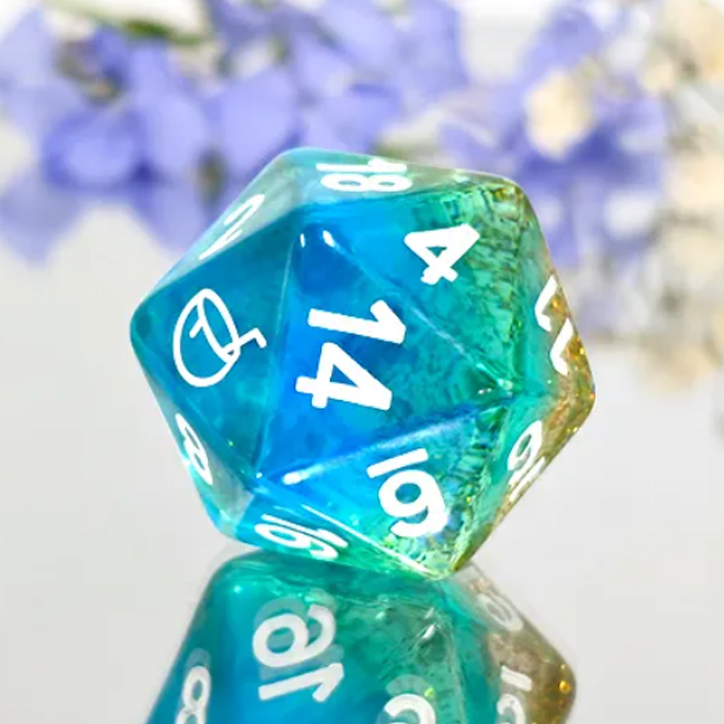 Desert Island Dice - Mini Glitter Filled Polyhedral D20 Close up with Flowers in the Background | Happy Piranha