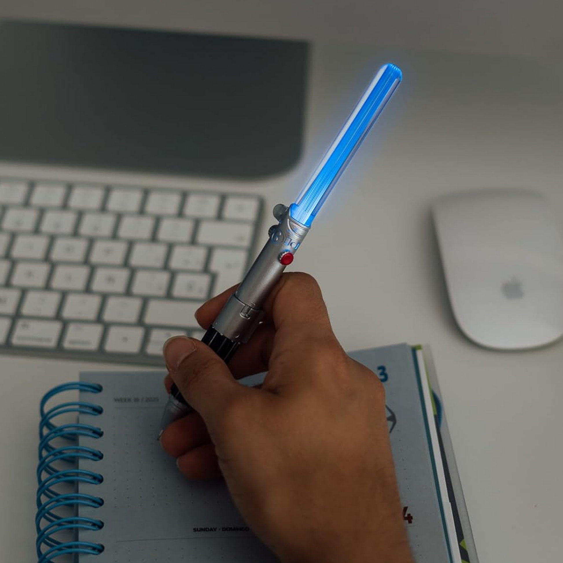 A Blue Star Wars Light Up  Lightsaber Pen in a Person's Hand, Glowing in a Dark Room | Happy Piranha