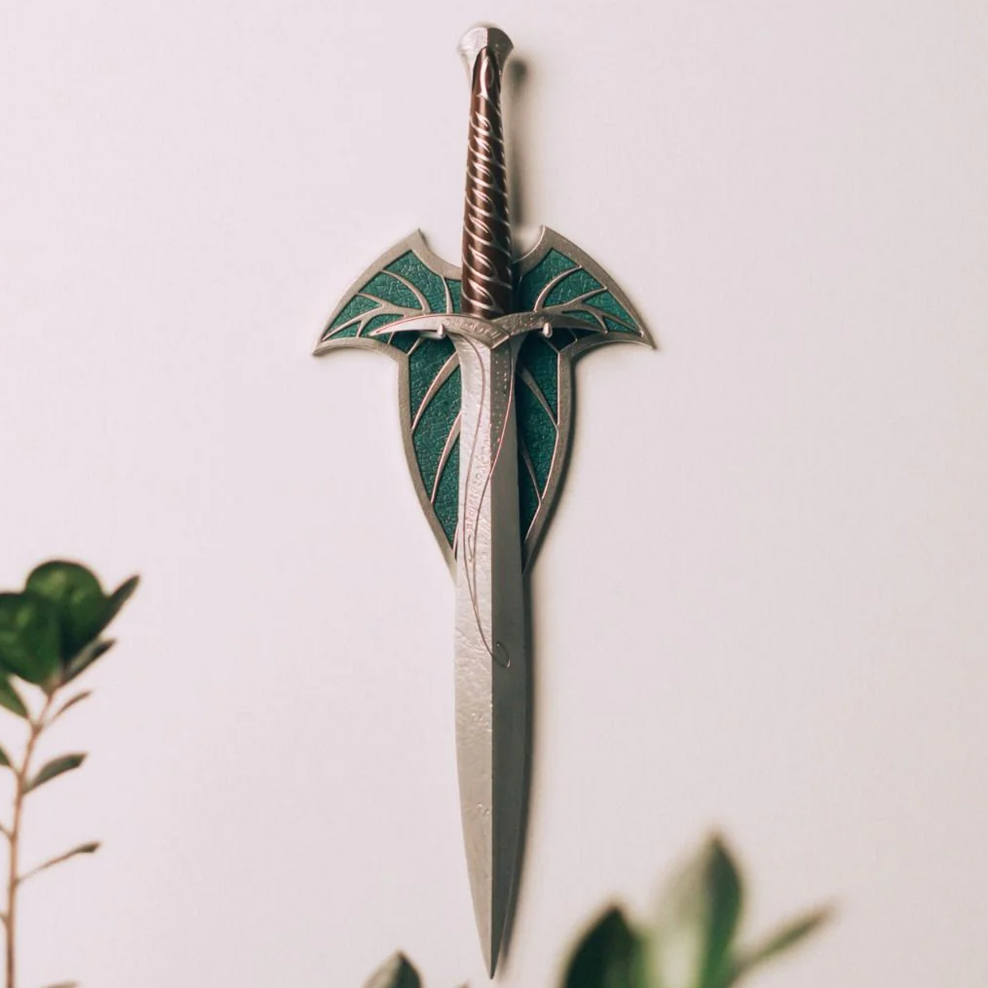 The Lord of the Rings Sting Frodo's Dagger 3D Wall Lamp Hanging on a White Wall With Plants in the Foreground | Happy Piranha