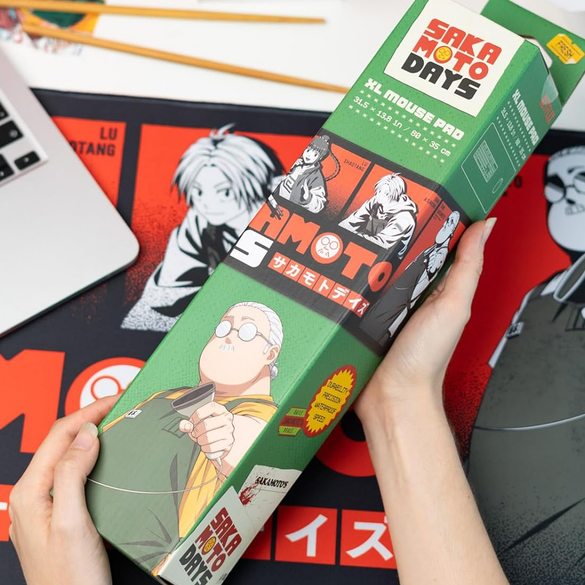 Sakamoto Days XXL Anime Mouse Pad & Keyboard Mat in its Box Being Held in a Persons Hands | Happy Piranha