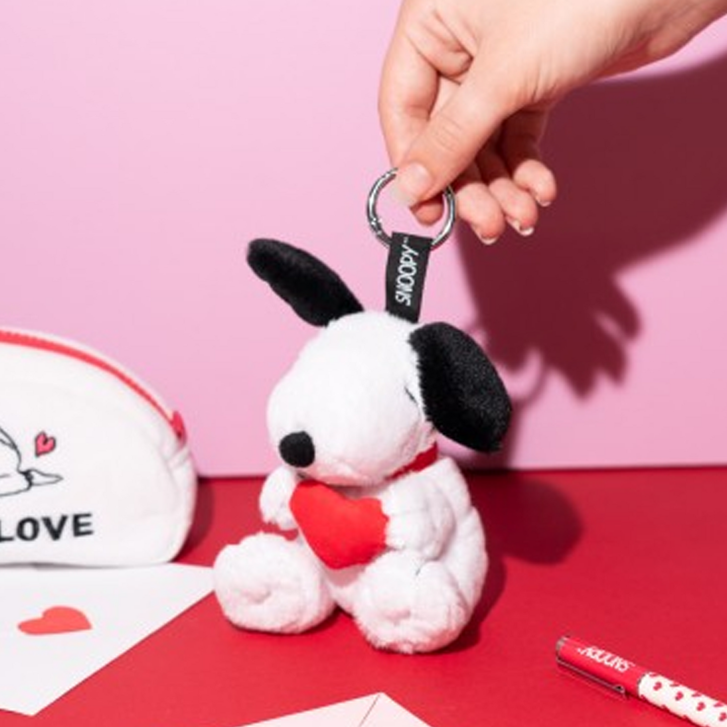 Peanuts: Snoopy Love Season Plush Keychain (Being Held in a Persons Hand on a Pink and Red Background) | Happy Piranha