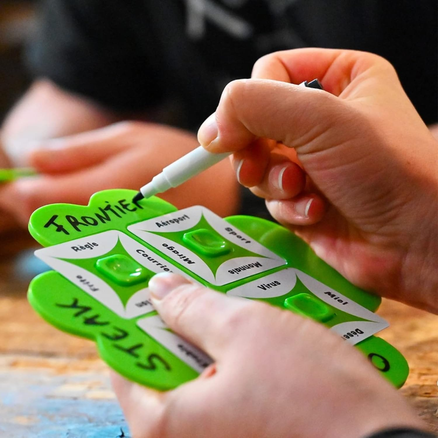 So Clover! A Cooperative Word-Association Board Game - A Close Up of a Person Writing with a Dry-Wipe Marker on the Plastic Clover Leaf Board | Happy Piranha
