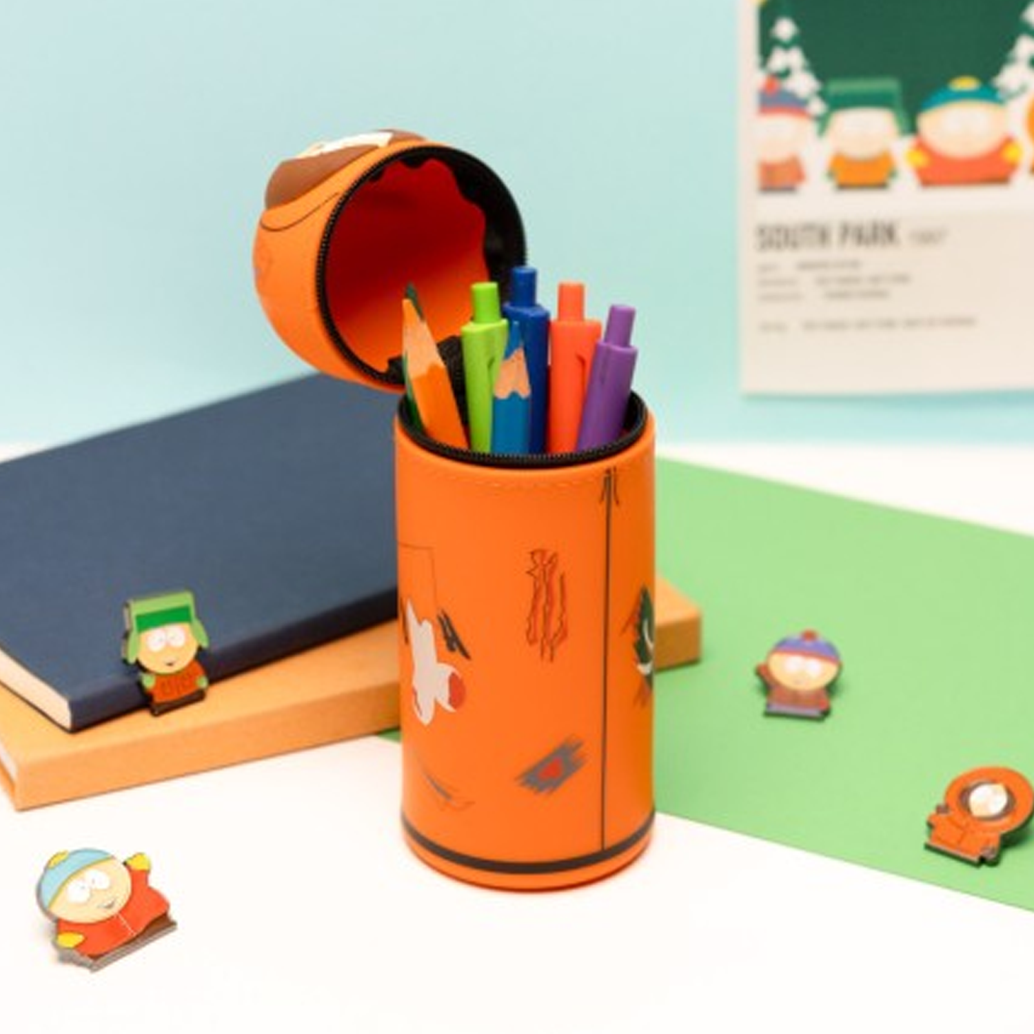 South Park Kenny 3D Silicon Pencil Case Open With Pens and Pencils Inside on a Blue and Green Background and Surrounded by Books and South Park Characters | Happy Piranha