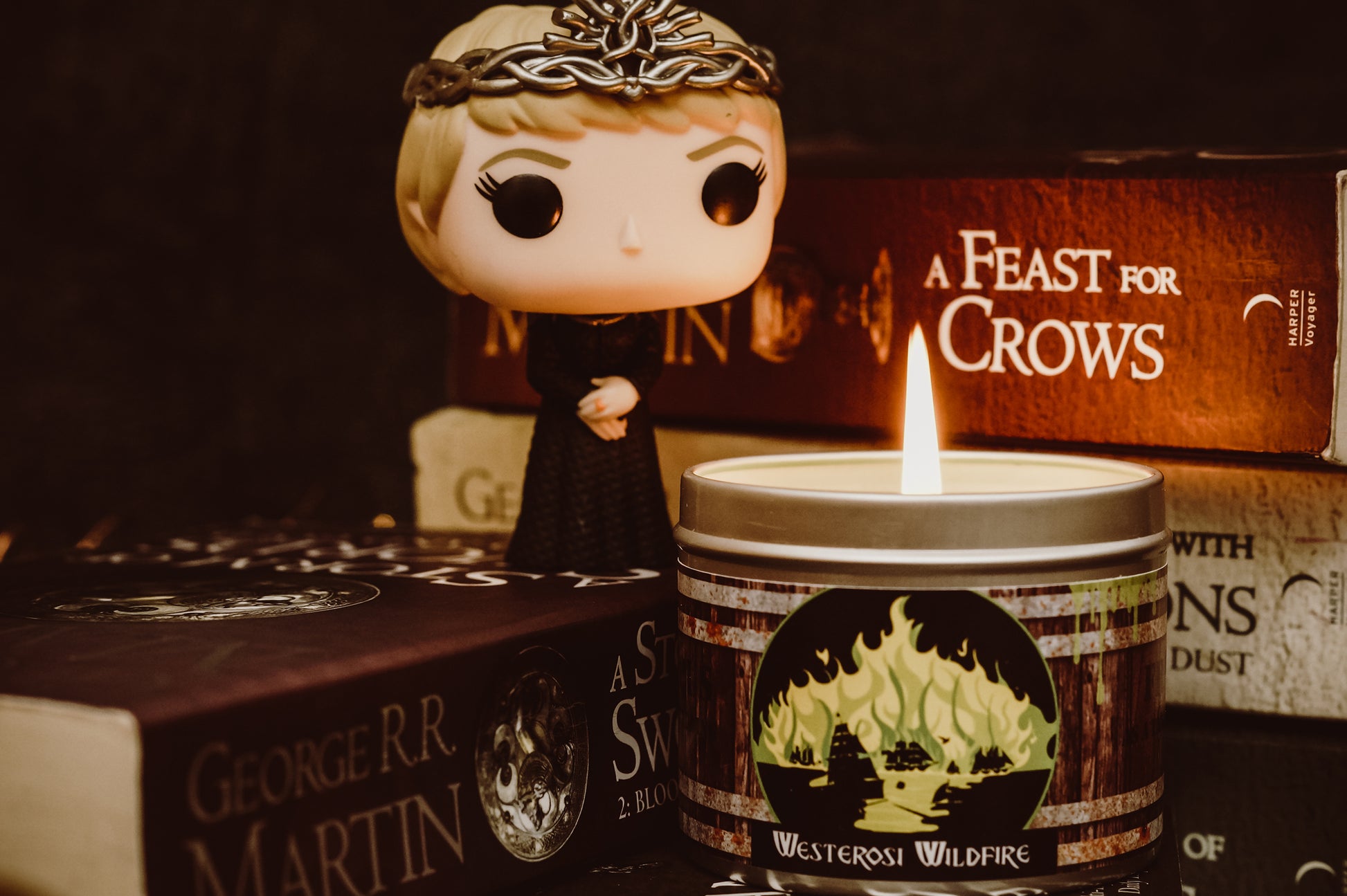 Happy Piranha's Westerosi wildfire scented candle alight by books